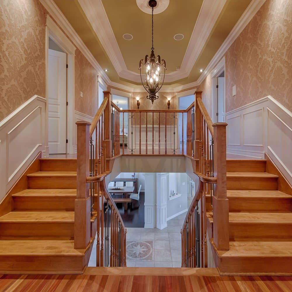 Staircase with wood banister and chandelier